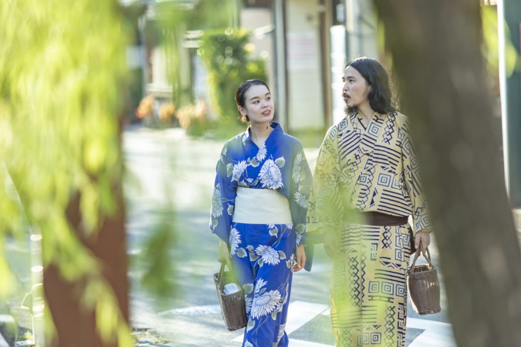 柳並木を歩きながら会話を楽しむ浴衣姿のご夫婦