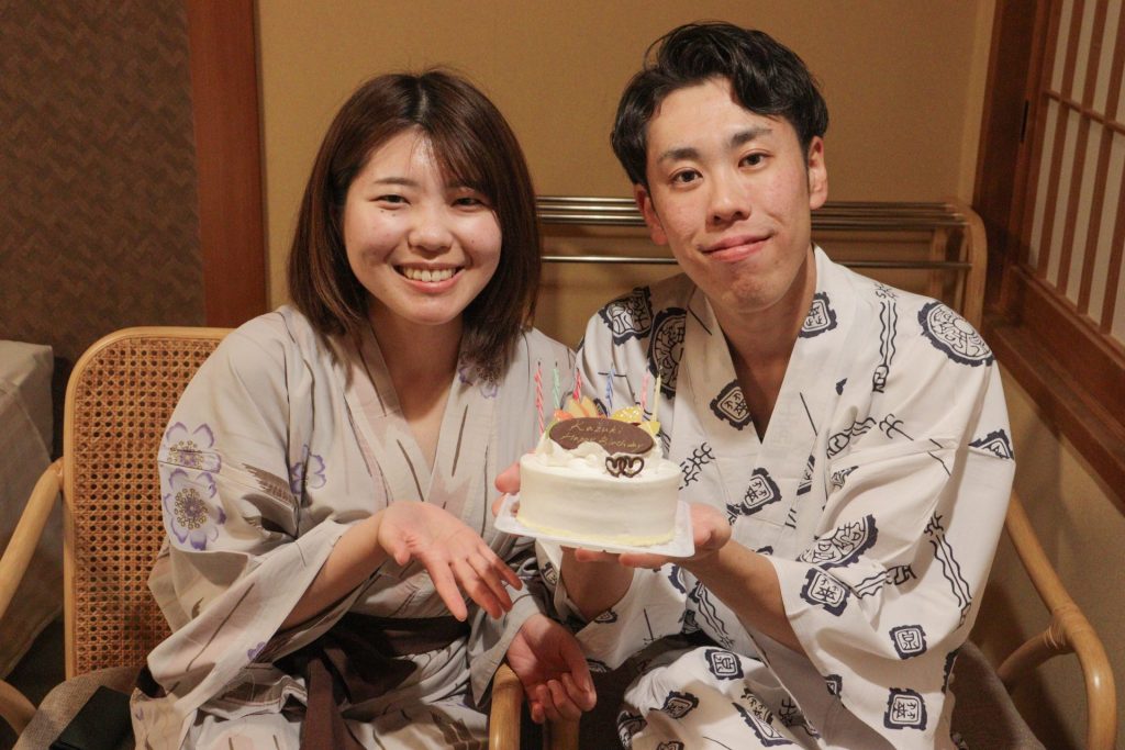 誕生日ケーキを囲み笑顔を見せるカップル