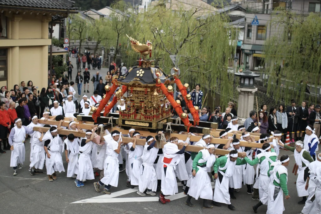 城崎秋祭りで、白装束の担ぎ手たちが四所神社の神輿を担ぎ、温泉街を巡行する様子