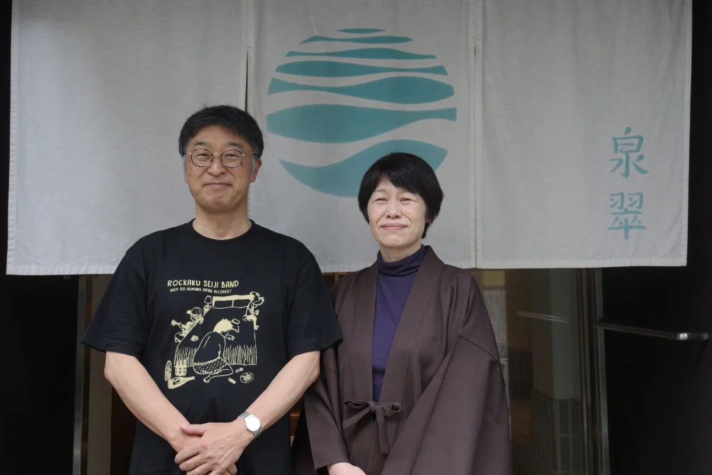 初めての城崎温泉旅行で泉翠を訪れ、旅館の暖簾の前で並んで記念撮影するご夫婦